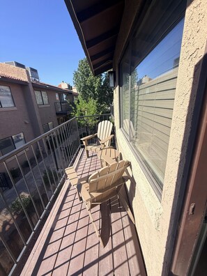 Ein Balkon mit Blick auf umliegende Gebäude, ein Holzstuhl und ein Tisch.