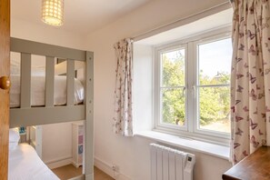 A room with a bunk bed, a window with curtains, a radiator, and a wooden door. - 3 Bed in Ventnor (oc-ic179) (Godshill)