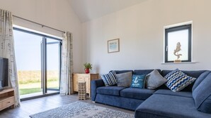 En moderne stue med en blå sofa, et mønstret tæppe, et træskab og et fjernsyn.