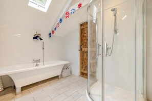 Un baño moderno con una bañera independiente, una ducha con mampara de vidrio y decoración temática náutica.