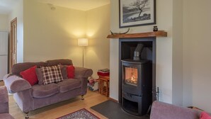 Ein Wohnzimmer mit einer Couch, einem Kamin, einer Lampe und einem gerahmten Bild an der Wand.