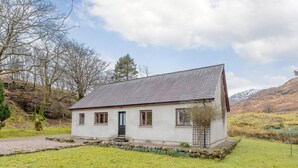 Ein eingeschossiges Haus mit geneigtem Dach, einer Haustür und einer kleinen Veranda.