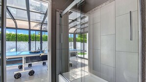 Een moderne kamer met een glazen deur naar een buitenruimte, een tafel met een blauwe tafelkleed en fitnessapparatuur.