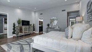 Een moderne slaapkamer met een groot bed, een televisie, een console tafel en een spiegel.