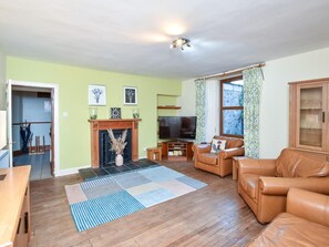 A living room with a fireplace, leather sofas, a TV, and a patterned rug.