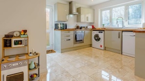 A modern kitchen with a microwave, oven, washing machine, and a wooden play kitchen set. - 4 Bed in Freshwater (oc-91115) (Freshwater)
