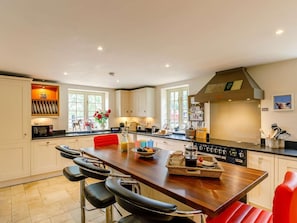 A spacious kitchen with a central island, white cabinetry, and a red chair. - 3 Bed in Harrogate (oc-g0123) (Ripley)