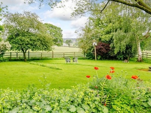 A lush green garden with a wooden fence, a birdhouse, and a small table with chairs.