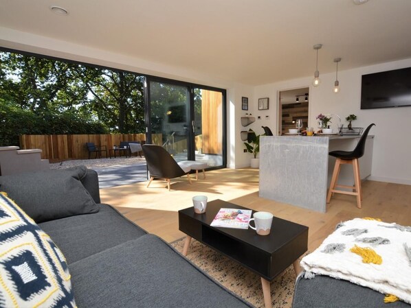 A modern living room with a sofa, coffee table, and a dining area with a kitchen counter.