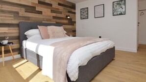 Un dormitorio moderno con un panel de madera, una cama gris y dos cuadros enmarcados en la pared.