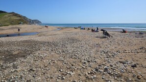 Una playa rocosa con tiendas de campaña y gente.