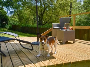 Una terraza con un perro, mobiliario exterior y una valla de madera.