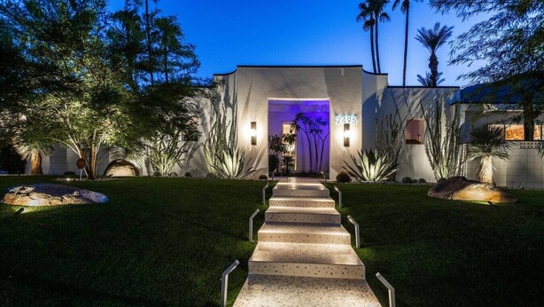 A modern house with a well-lit entrance, a number 2495 sign, and a pathway leading to the door. - 4,775 Sq Ft MidMod Estate, 5 King Beds, All En Suites, Saltwater Pool, Spa (Palm Springs)