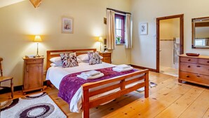 Een slaapkamer met een houten bed, bedlampen, een dressoir en een raam met gordijnen.