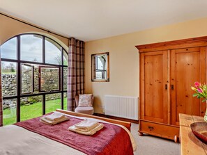 A bedroom with a large window, a wooden wardrobe, a radiator, and a bed with towels. - 2 Bed in Skipton (oc-94261) (Airton)
