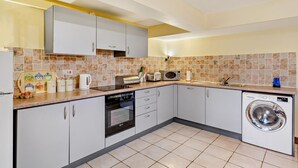Una cocina moderna con armarios blancos, microondas, tostadora y lavadora.