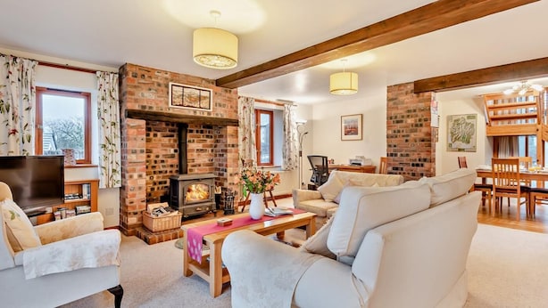 Una sala acogedora con chimenea, un sofá, un televisor y un comedor.