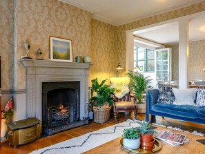 Ein Wohnzimmer mit Kamin, einem blauen Sofa und einem Essbereich mit Tisch und Stühlen.