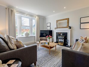 Ein Wohnzimmer mit Kamin, Fernseher und einer Couch.