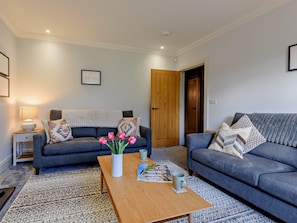 Ein Wohnzimmer mit zwei Sofas, einem Couchtisch und einer Tür.