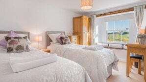 Ein Schlafzimmer mit zwei Betten, einem Holzschrank, einem Schreibtisch und einem Fenster mit Blick.
