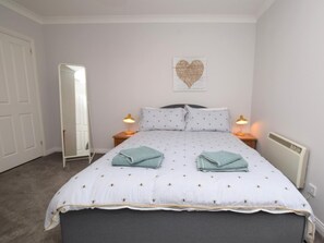 Ein Schlafzimmer mit einem Bett, zwei Nachttischlampen, einem Spiegel und einer Wanddekoration.
