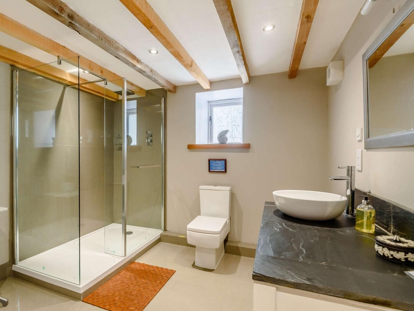 A modern bathroom with a glass-enclosed shower, a white toilet, and a large vessel sink.