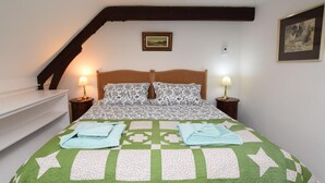 Une chambre à coucher avec un lit, deux lampes de chevet, un tableau au mur et un escalier.