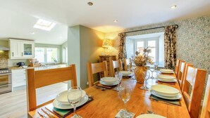 A dining area with a wooden table set for six, surrounded by chairs.