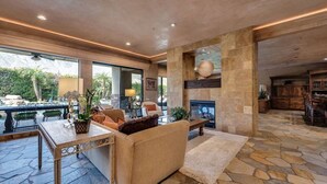 A spacious living area with a stone floor, a fireplace, and a view of the outdoors. - 5 BR Custom Mediterranean Estate In Andreas Hills, 5 King Beds Putting Green... (Palm Springs)