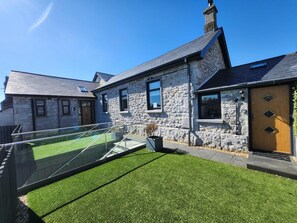 A stone house with a modern design, featuring a glass balcony and a well-maintained lawn. - 4 Bed in Grange-over-sands (oc-90892) (Allithwaite)
