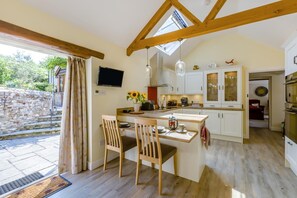 A kitchen with a wooden table, chairs, a TV, and cabinets.