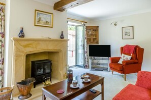 A living room with a fireplace, a television, a red armchair, and a coffee table.