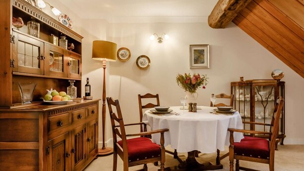 Un coin repas comprenant une table ronde, des chaises, une lampe et un meuble avec des portes en verre.