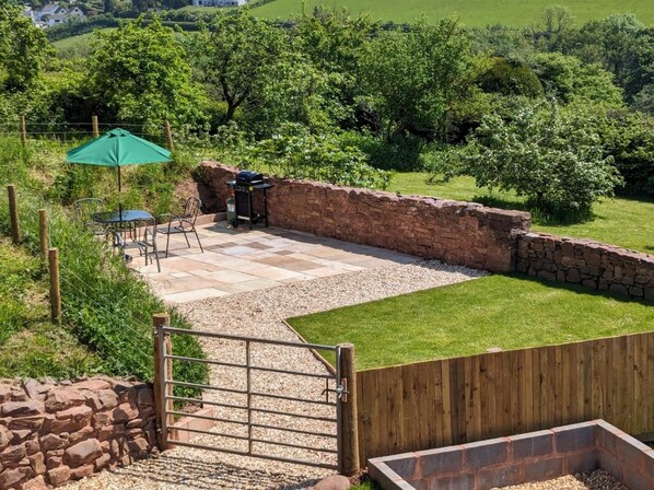 Un patio con una mesa y sillas de piedra, una parrilla y una valla de madera.