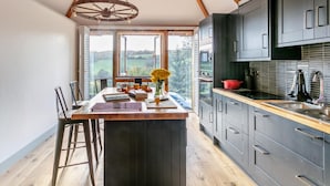 Una cocina con armarios oscuros, una isla de madera y vistas al exterior.