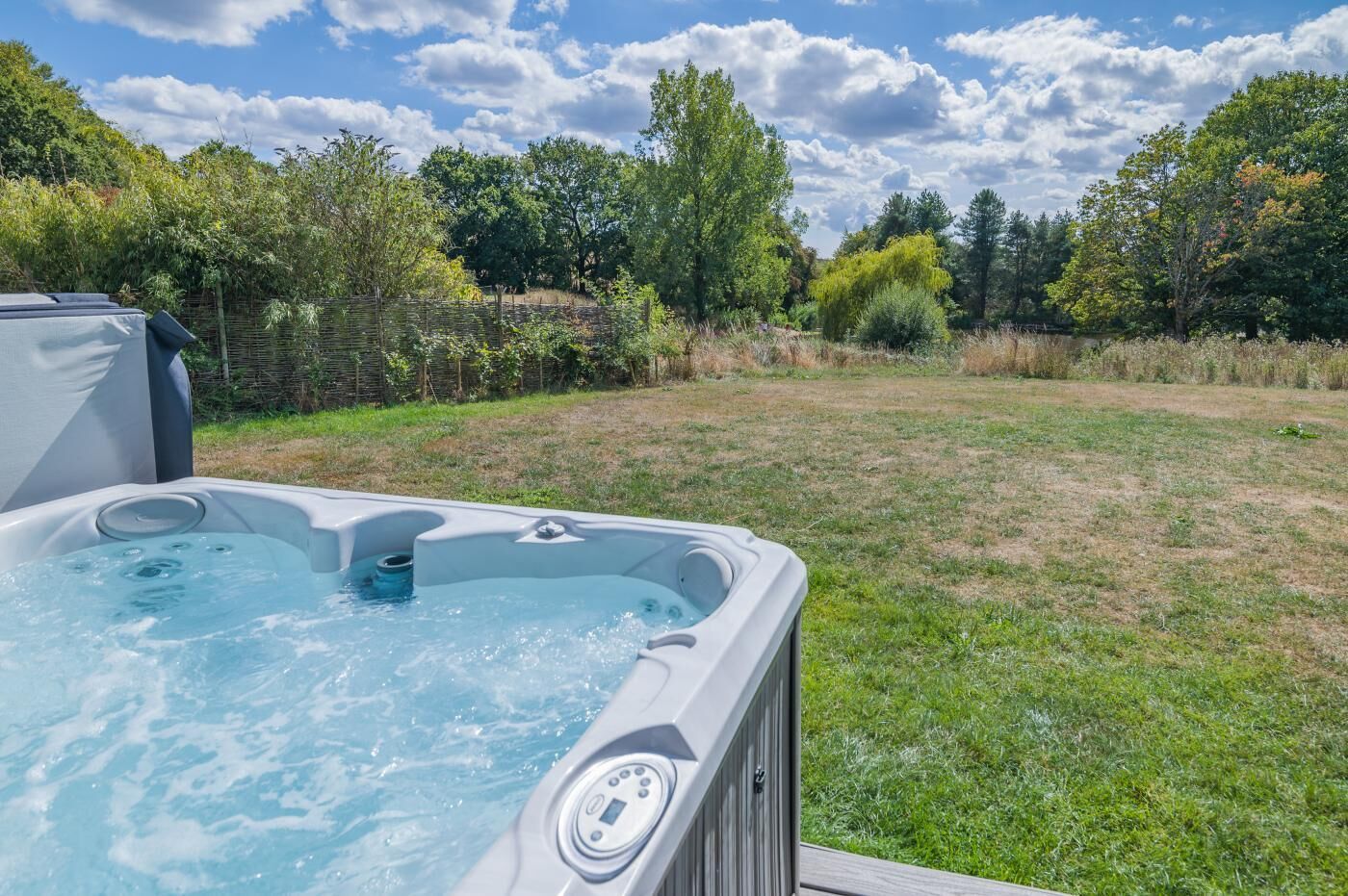 Un bain à remous dans une cour arrière verdoyante, avec des arbres en arrière-plan.