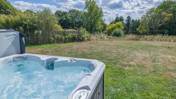 Un bain à remous dans une cour arrière verdoyante, avec des arbres en arrière-plan.