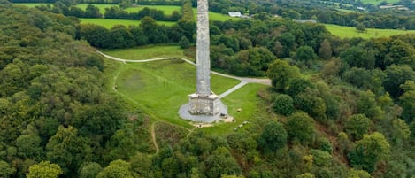 Una torre alta y esbelta rodeada de abundante vegetación y un sendero serpenteante.