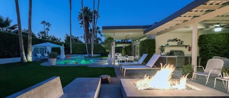 A patio area with outdoor seating, a fire feature, and a pool.