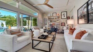 Ein modernes Wohnzimmer mit weißen Sofas, einem Couchtisch und einem Deckenventilator.