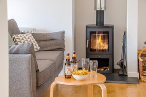 Ein gemütliches Wohnzimmer mit einer Couch, einem Tisch mit Snacks und Getränken sowie einem Kaminofen.