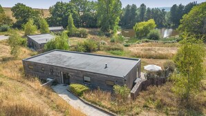 Un edificio moderno con techo plano, rodeado de paisaje natural y una masa de agua.