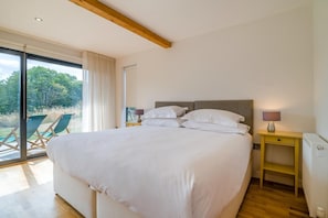 A large bed with white linens, a wooden headboard, and two bedside tables with lamps.