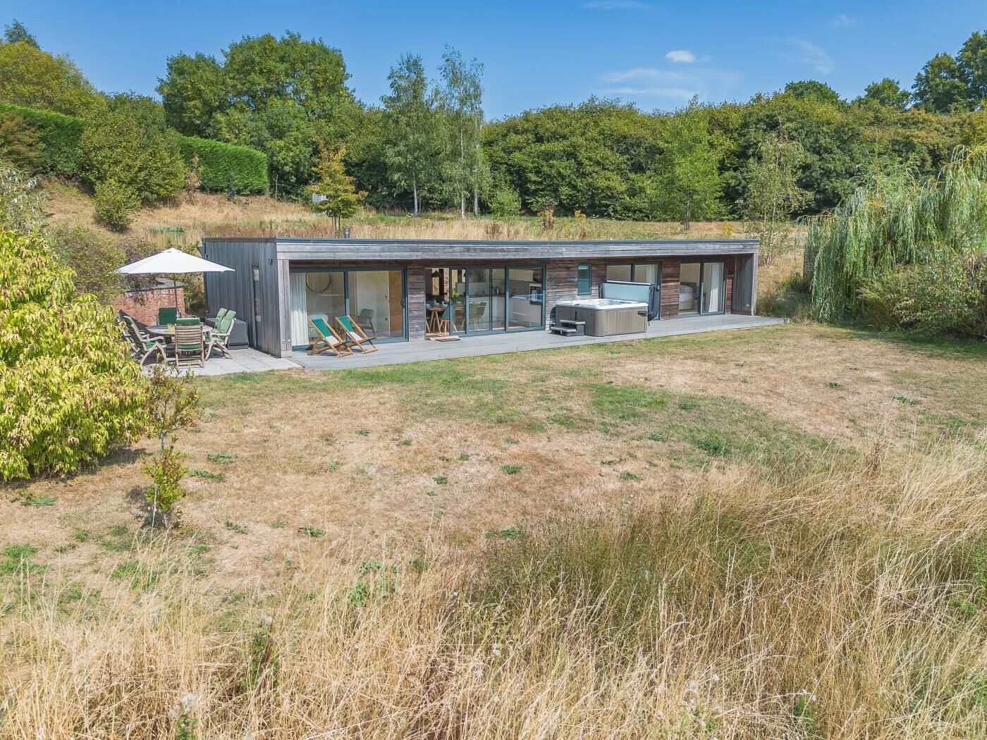 Une maison moderne dotée d’un patio, d’un espace salon extérieur et d’un jacuzzi.