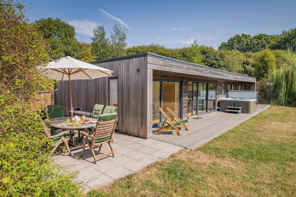 A modern outdoor patio with a dining table, chairs, and a large umbrella.
