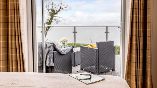 En balkon med et bord, stole og et par briller på sengen.