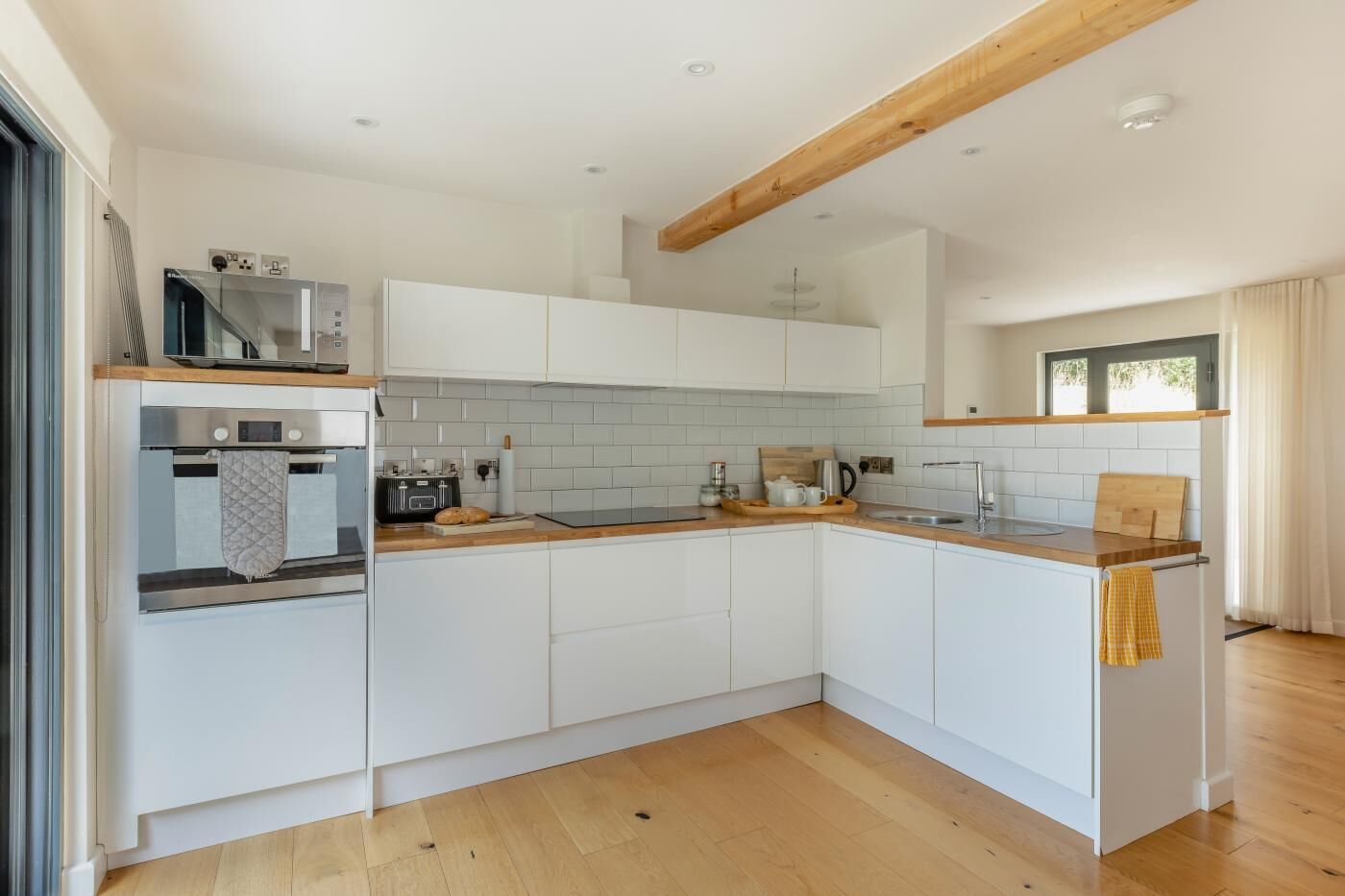 A modern kitchen with white cabinets, a wooden countertop, and a built-in oven.