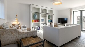 Una sala de estar moderna con un sofá, una mesa de centro, una estantería y un televisor.
