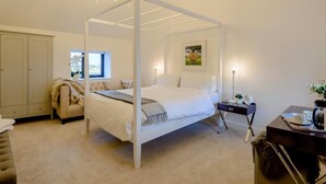 Un dormitorio con cama con dosel, un armario, un escritorio con lámpara y una ventana con vistas.